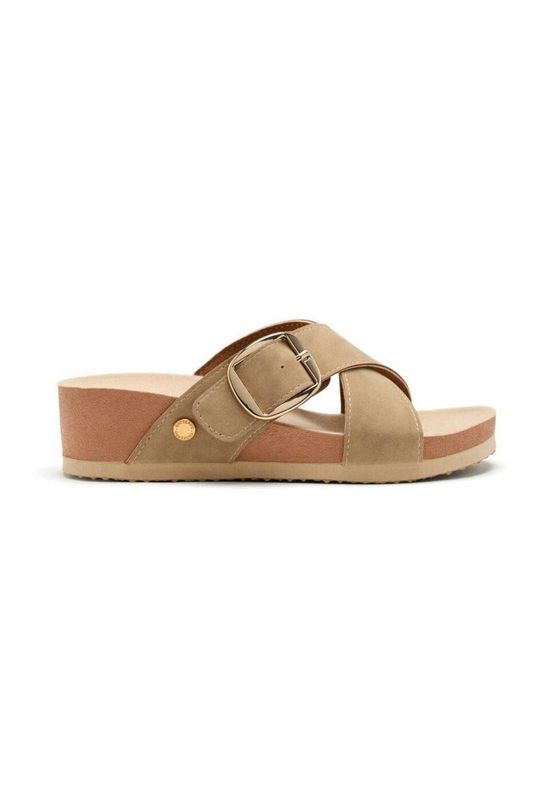 Sandal de plataforma beige con diseño de tiras cruzadas, hebilla metálica y parte superior suave y texturizada. Suela de color marrón claro con ligero agarre.
