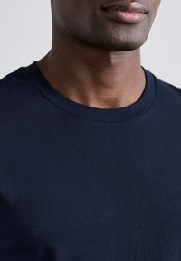 Navy modrá bavlněná tričko s crew neck, s hladkou texturou a krátkými rukávy, se žebrovaným límcem a minimálními švy.