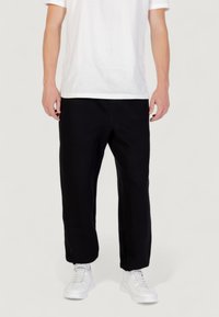 Zwarte sweatpants gemaakt van zachte stof, met een relaxed fit en rechte pijpen, gecombineerd met witte sneakers en een eenvoudig wit t-shirt.