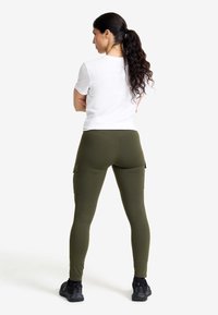 Olivgröna cargoleggings med sidofickor och ett slitstarkt, elastiskt material. Kombineras med en figurnära vit t-shirt i en enkel design.