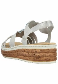 Sandale plateforme blanche avec une semelle à texture liège, des brides élastiques et un accent argent métallique. La vue arrière met en évidence la conception de la semelle superposée.