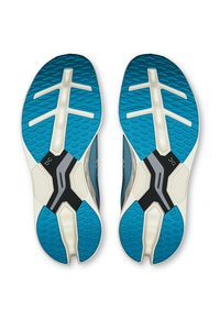 Semelles de chaussures avec un motif de traction en caoutchouc bleu, des accents beiges et un élément central noir. Surface texturée pour une meilleure adhérence et durabilité.