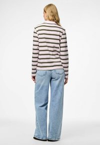 Ilgais rankovės dryžuotas marškinėliai su rožinėmis, alyvuogių ir kreminėmis horizontaliomis juostelėmis; derinami su šviesiai mėlynomis plačiomis kelnėmis.