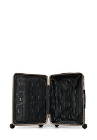 Open beige harde koffer met zwarte binnenvoering, met een ritscompartiment aan de linkerkant en verstelbare cross straps aan de rechterkant.