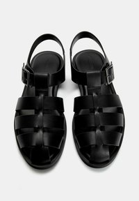 Sorte sandaler med et vævet stropdesign, lavet af glat materiale, åben bag, med en justerbar spænde på ankelstroppen.