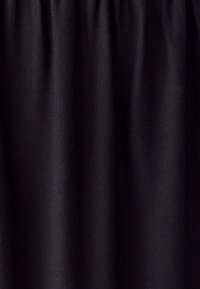 Černá tkanina s vertikálními záhyby, které ukazují texturu a jemné stíny, naznačující měkký, tkaný materiál.