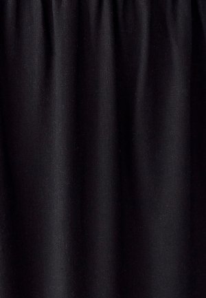 Zwarte stof met verticale plooien die textuur en subtiele schaduwen tonen, wat suggereert dat het een zachte, geweven materiaal is.