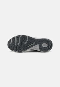 Sola da bota de caminhada Columbia em borracha preta e cinza. Apresenta um padrão de piso texturizado com grips hexagonais e circulares. Logotipo exibido de forma proeminente.