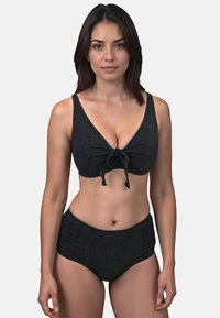 Costume da bagno nero a due pezzi con top triangolare e allacciatura frontale, pantaloni alti a vita larga, tessuto testurizzato con leggera lucentezza.