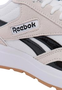 Reebok-Sneaker mit weißem Mesh-Obermaterial, beigen Wildlederakzenten, schwarzen Streifen und weißer Gummisohle mit strukturiertem Kaugummi-Außensohlenprofil.