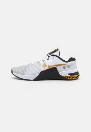 Chaussure de sport blanche et noire avec des accents orange, dessus en mesh et semelle texturée, vue de côté gauche sur fond blanc.