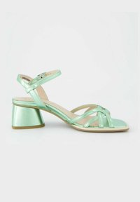 Svetle zelené sandály na podpatku s řemínkovým designem, nastavitelným popruhem kolem kotníku a čtvercovým blokovým podpatkem. Vyrobené z lesklého syntetického materiálu.