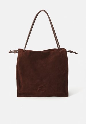Brown suede handbag with a soft texture, rectangular shape, and two slender handles, featuring minimal stitching and an embossed logo detail.