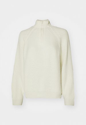 Pull en maille couleur crème avec col montant, zip moitié, texture côtelée et épaules tombantes pour un ajustement décontracté.