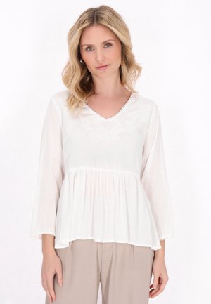 Blusa bianca in tessuto leggero, con scollatura a V, dettagli ricamati e maniche lunghe svasate con vita arricciata.
