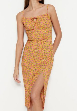 Robe sans manches à motif floral en jaune avec des accents roses et verts, dotée d'un corsage ajusté et d'un fente sur le côté pour plus de détail.