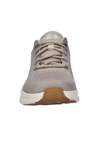Scarpa sportiva beige con tomaia in rete, dettagli blu, lacci strutturati e un intersuola bianca imbottita; suola in gomma con pattern per la presa.