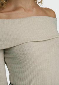 Smėlinis off-the-shoulder megztinis su horizontaliu raštu, platu iškirpimu ir prisitaikančia siluetu. Minkšta, lengva megztinė medžiaga.