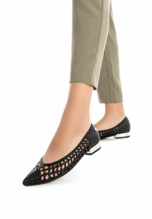 Bailarinas negras de punta abierta, hechas de material trenzado, con punta afilada y pequeño tacón cuadrado con detalles plateados.