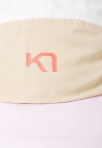Lichte pet met een witte en beige bovenkant en een roze klep. De pet heeft een subtiele logo in het roze aan de voorkant.