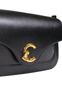 Borsa a mano in pelle nera con texture liscia, pattina curva e una vistosa chiusura con logo dorato. Il design comprende dettagli cuciti.