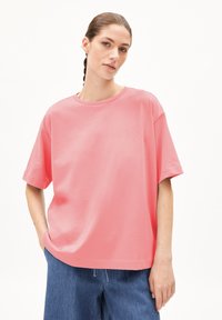 Roze oversized T-shirt van katoen, met korte mouwen, een ronde hals en een gladde textuur, gedragen met losse denim pantalons.