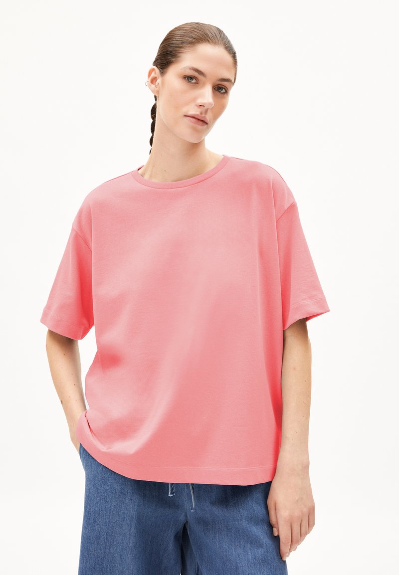 Roze oversized T-shirt van katoen, met korte mouwen, een ronde hals en een gladde textuur, gedragen met losse denim pantalons.