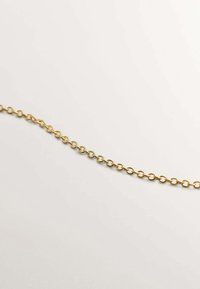 Cadena de oro con eslabones ovalados, textura suave, forma uniforme y un acabado pulido, dispuesta plana sobre un fondo claro.