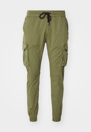Pantalones cargo verde oliva hechos de una mezcla de algodón con una cintura elástica, cordón y dos bolsillos laterales con solapas.