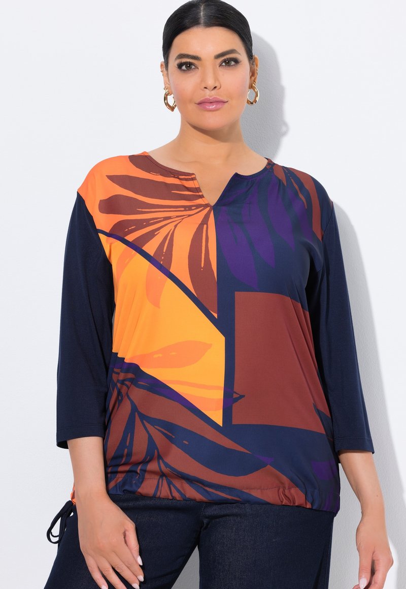 Top multicolore con scollo a V, maniche a tre quarti e motivo floreale in arancione, blu navy e viola. Tessuto morbido con dettagli a cordoncino.