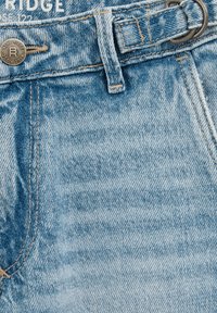 Pantaloni in denim azzurro chiaro con una finitura sbiadita e testurizzata, dotati di un bottone metallico, dettagli cuciti e un design con passanti per cintura.