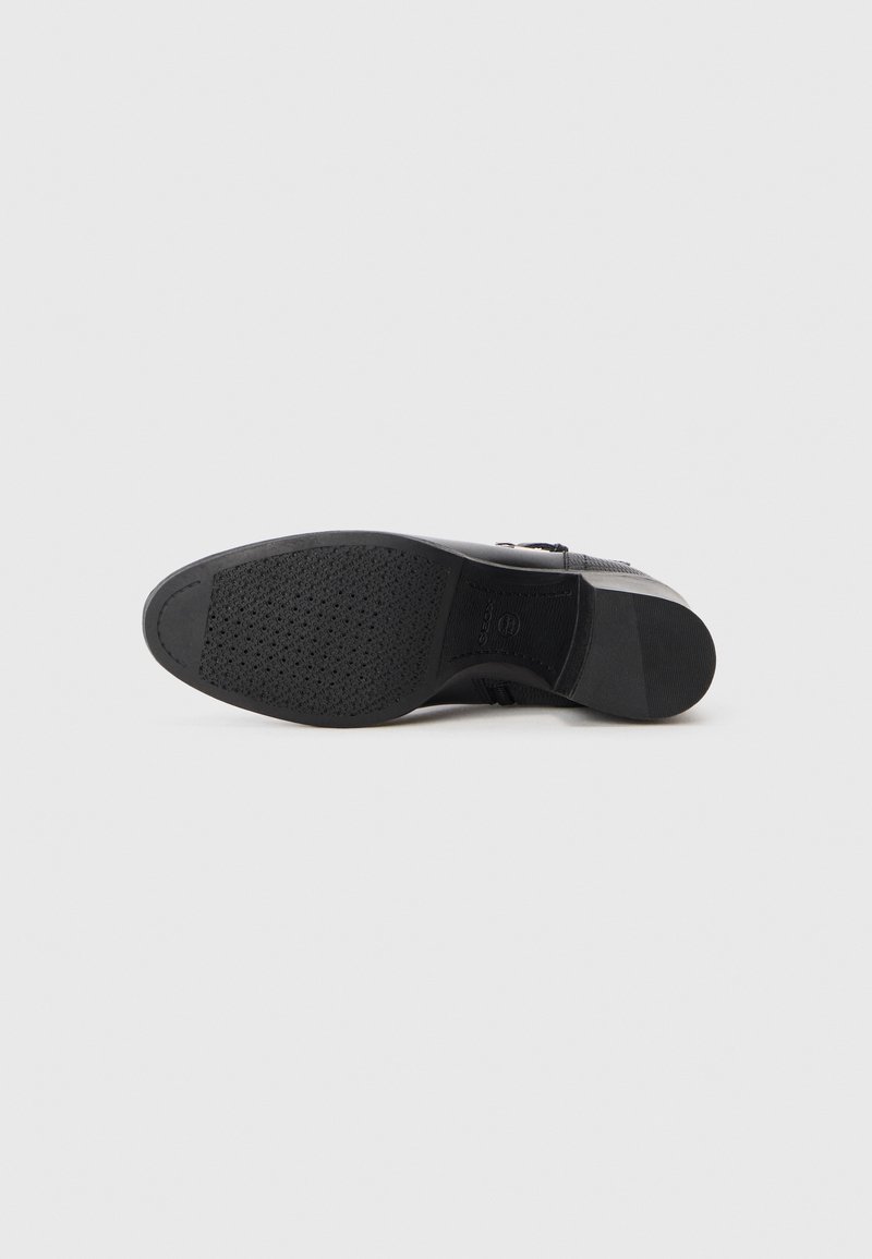 Chaussure noire avec une semelle en caoutchouc texturée, un matériau supérieur lisse et une fermeture éclair sur le côté pour un accès facile. Design à bout rond avec des accents minimaux.
