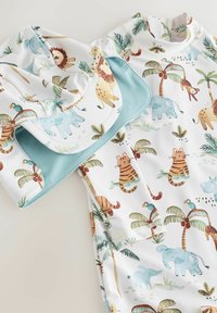 Conjunto de ropa de baño infantil en tela blanca con ilustraciones coloridas de animales, incluidos leones, elefantes y tigres, con detalles en color azul verdoso.