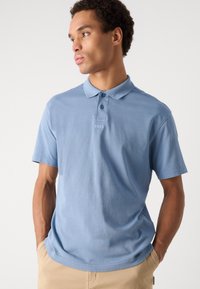 Polo de culoare albastru deschis, fabricat din bumbac moale, având un guler clasic, deschidere cu două butoane și un logo BOSS subtil pe piept.