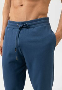 Donkerblauwe joggerbroek met een geribbelde tailleband, verstelbare trekkoord en zijzakken. Soepele textuur, casual ontwerp.