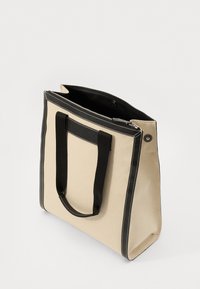 Geantă tote din pânză bej, cu accente din piele neagră, dotată cu mânere negre robuste și cusături albe pe margini. Design cu deschidere în partea de sus.