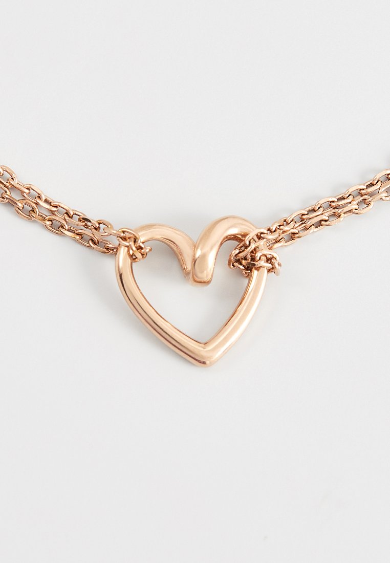 Halskette aus Roségold mit einem herzförmigen Anhänger. Sie verfügt über eine glatte, polierte Oberfläche und filigrane Kettenglieder, die Textur und Detail hinzufügen.