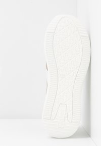 Semelle de basket blanche avec un motif de crampons géométrique, taille 4 1/2, marque Gabor, positionnée verticalement contre un fond d'angle blanc.