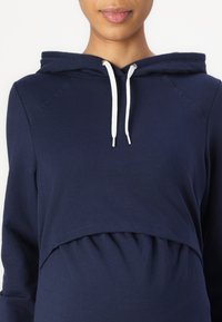 Námořnická modrá zkrácená mikina s kapucí z měkké tkaniny, s klokankou, stahovací šňůrkou a nařaseným lemem pro pohodlný střih.