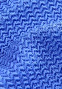 Tissu texturé de couleur bleue vibrante, arborant un motif en zigzag, finition douce et légère brillance, mettant en valeur une apparence ondulée et dimensionnelle.