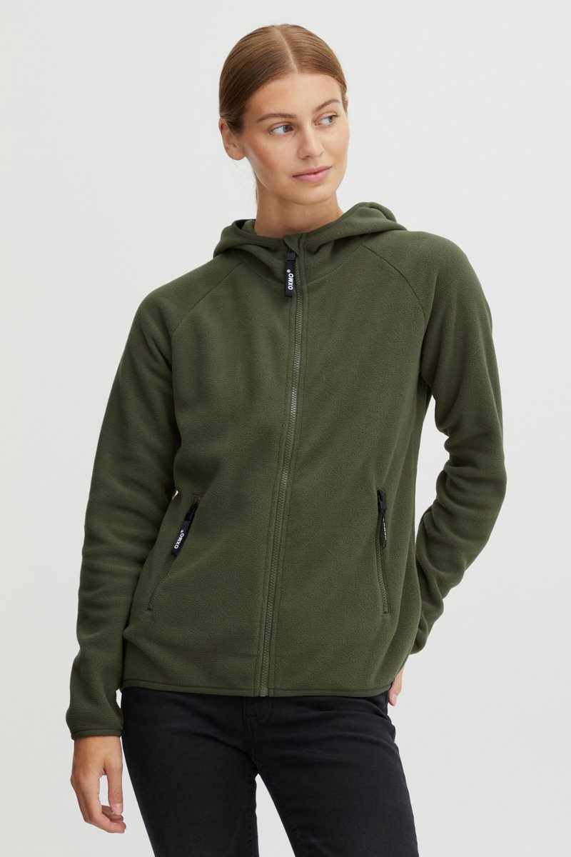 Felpa verde in pile con zip frontale, due tasche con zip, maniche raglan e cappuccio con coulisse. Il tessuto appare morbido e caldo.