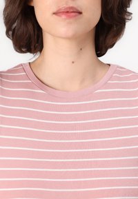 T-shirt a righe rosa chiaro con strisce bianche orizzontali, realizzata in tessuto morbido, con scollo rotondo e maniche corte.