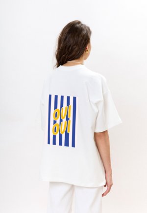 Witte katoenen t-shirt met een grote afbeelding op de rug, met blauwe en roze verticale strepen en het woord "oui" in het geel.