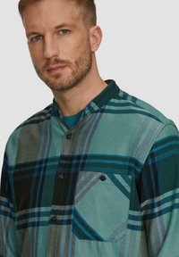 Groene geplaid shirt met blauwe en grijze strepen, met een button-down kraag, een borstzak en een zachte stofstructuur. Bevat contrasterende knoopdetails.