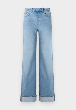 Jasnoniebieskie szersze dżinsy w klasycznym denimu z wysokim stanem, z wywiniętymi nogawkami i widocznymi szwami.