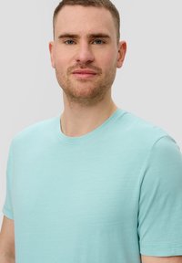 Hellblaues Baumwoll-T-Shirt mit rundem Ausschnitt und kurzen Ärmeln. Glatte Textur, minimalistisches Design, keine sichtbaren Muster oder Verzierungen.