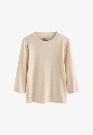 Béžová košeľa s dlhým rukávom z textúrovaného materiálu, s okrúhlym výstrihom a raglánovými rukávmi. Jednoduchý, neformálny dizajn bez vzorov alebo ozdôb.