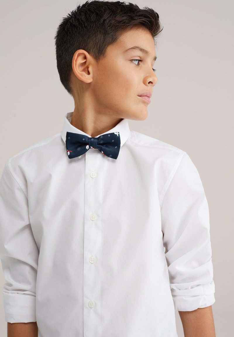 Tumši zilas tauriņkrāsas tauriņš ar krāsainiem rakstiem, kopā ar balto pogājamo kreklu. Krekls ar uzritinātām piedurknēm un gludu faktūru.