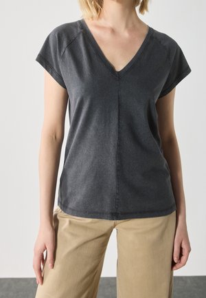 Grå bomulds V-hals t-shirt med korte ærmer, der har subtile syninger og en afslappet pasform, parret med lysebeige bukser.