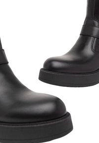 Stivali alla caviglia in pelle nera con punta rotonda, design minimalista e suola nera spessa. Presentano una texture liscia e dettagli di cucitura discreti.
